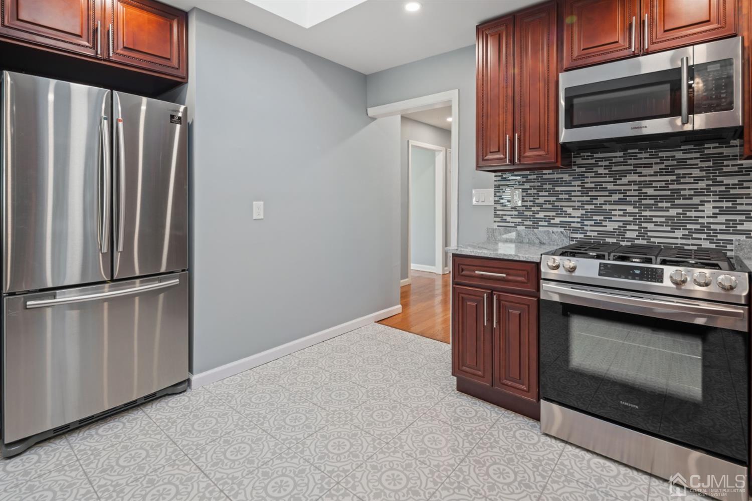 282 Lawrence Avenue North Plainfield, NJ 07063 - Photo 14 of 27 a kitchen with granite countertop a stove top oven cabinetry a sink and a refrigerator