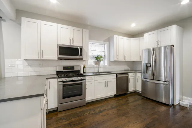 a kitchen with white cabinets appliances a sink and a window
