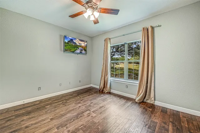 a view of an empty room with a window and wooden floor