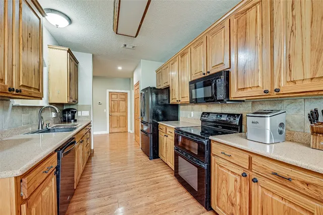 a kitchen with stainless steel appliances granite countertop wooden cabinets a sink dishwasher a stove and a refrigerator