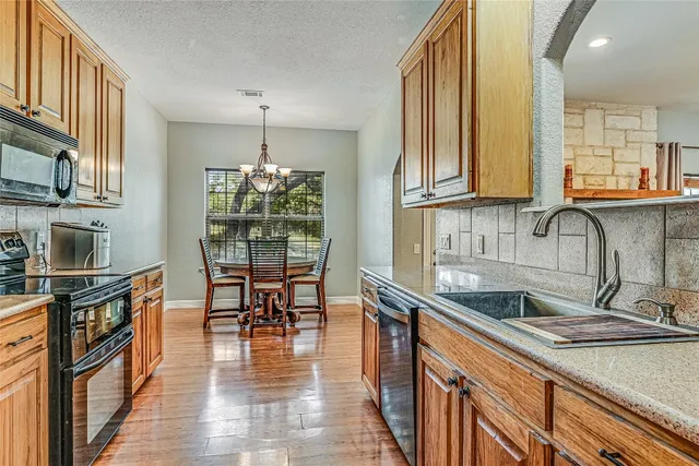 a kitchen with stainless steel appliances granite countertop a sink stove and cabinets