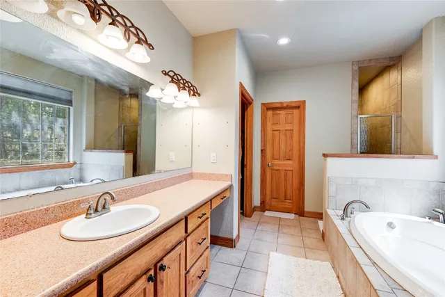 a bathroom with a sink double vanity granite tub shower and a mirror