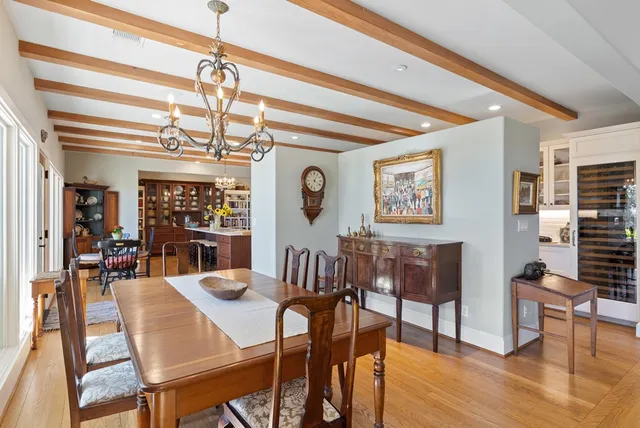 a dining room with wooden floor a chandelier a glass table and chairs