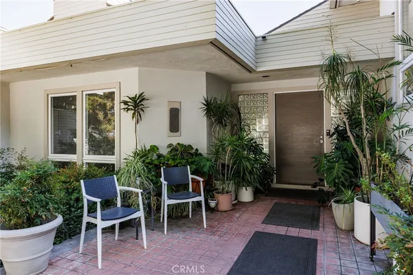 a view of a patio with table and chairs potted plants and floor to ceiling window