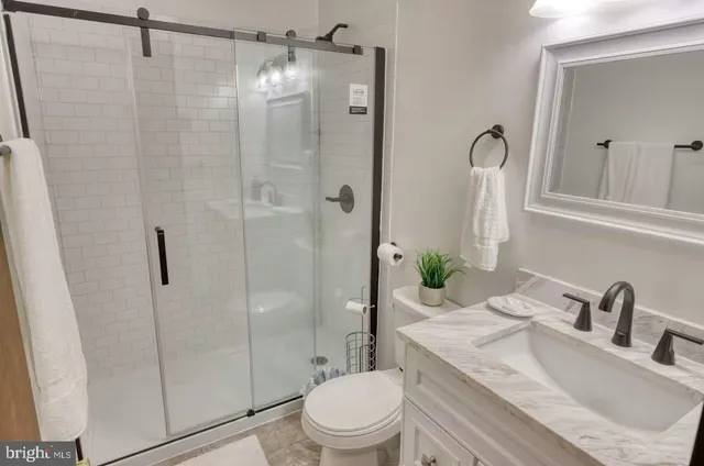 a bathroom with a granite countertop sink toilet and shower