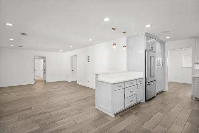 a large kitchen with stainless steel appliances granite countertop a large counter top and wooden floors