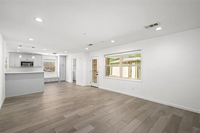 a view of an empty room with a window and wooden floor