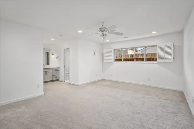 an empty room with windows and ceiling fan
