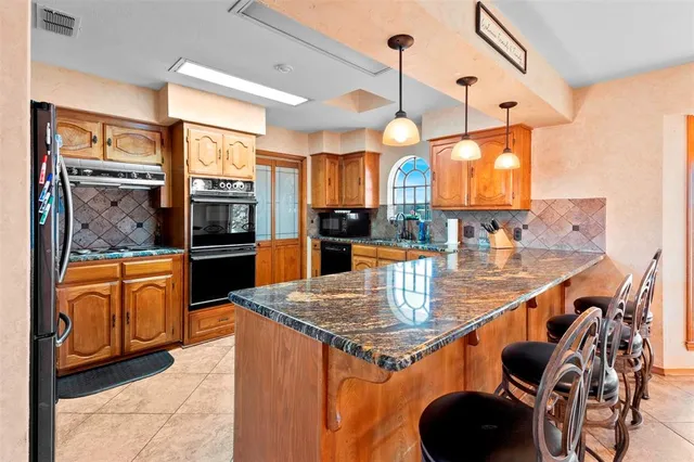 a kitchen with stainless steel appliances granite countertop a sink a stove and a wooden floors