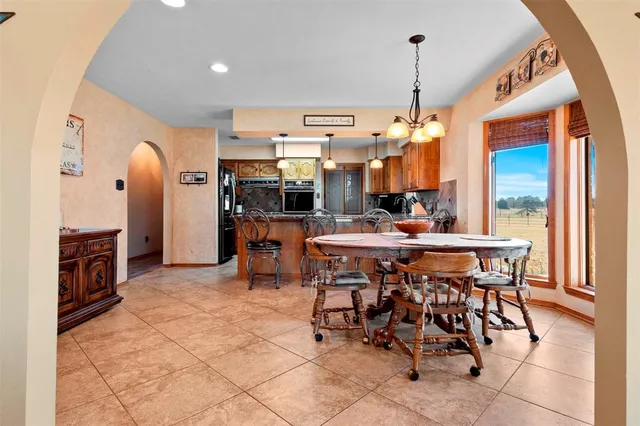 a dining hall with stainless steel appliances kitchen island granite countertop a table chairs and a chandelier