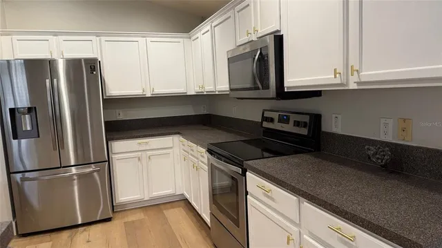a kitchen with granite countertop white cabinets and stainless steel appliances