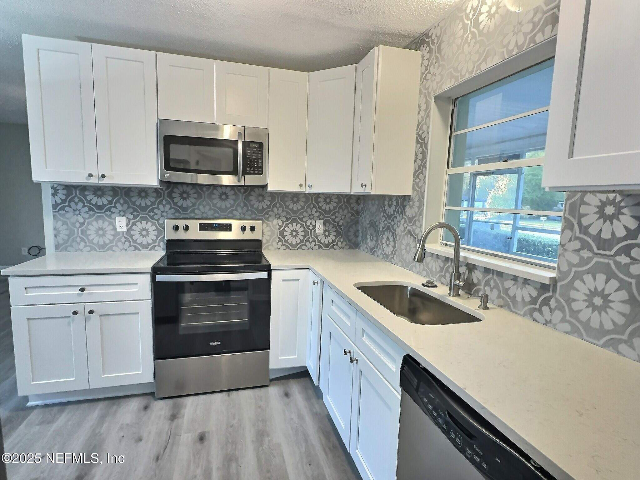 7456 Centauri Road Jacksonville, FL 32210 - Photo 11 of 26 a kitchen with granite countertop a sink dishwasher a stove and a microwave oven with cabinets