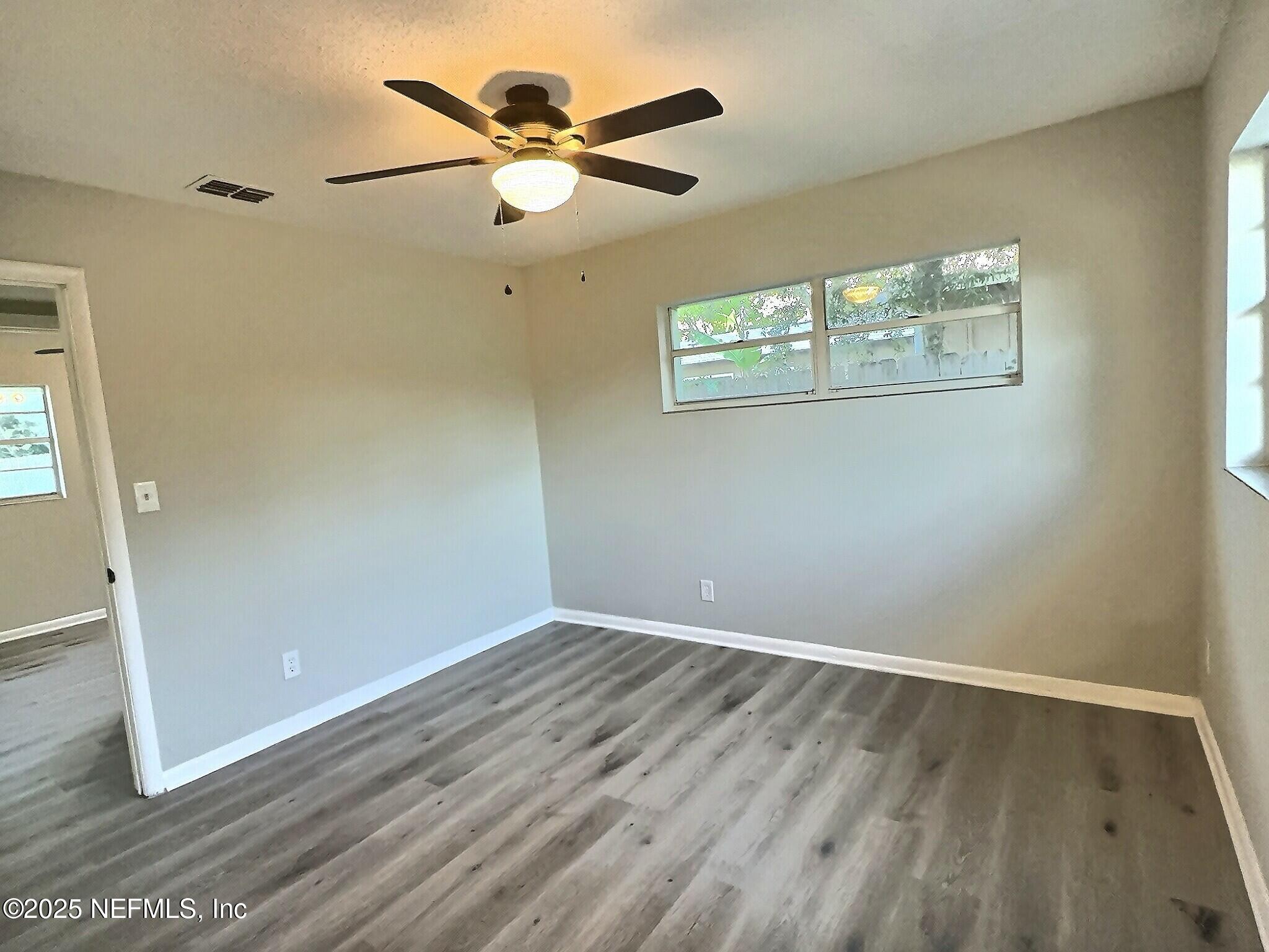 7456 Centauri Road Jacksonville, FL 32210 - Photo 12 of 26 an empty room with wooden floor fan and windows
