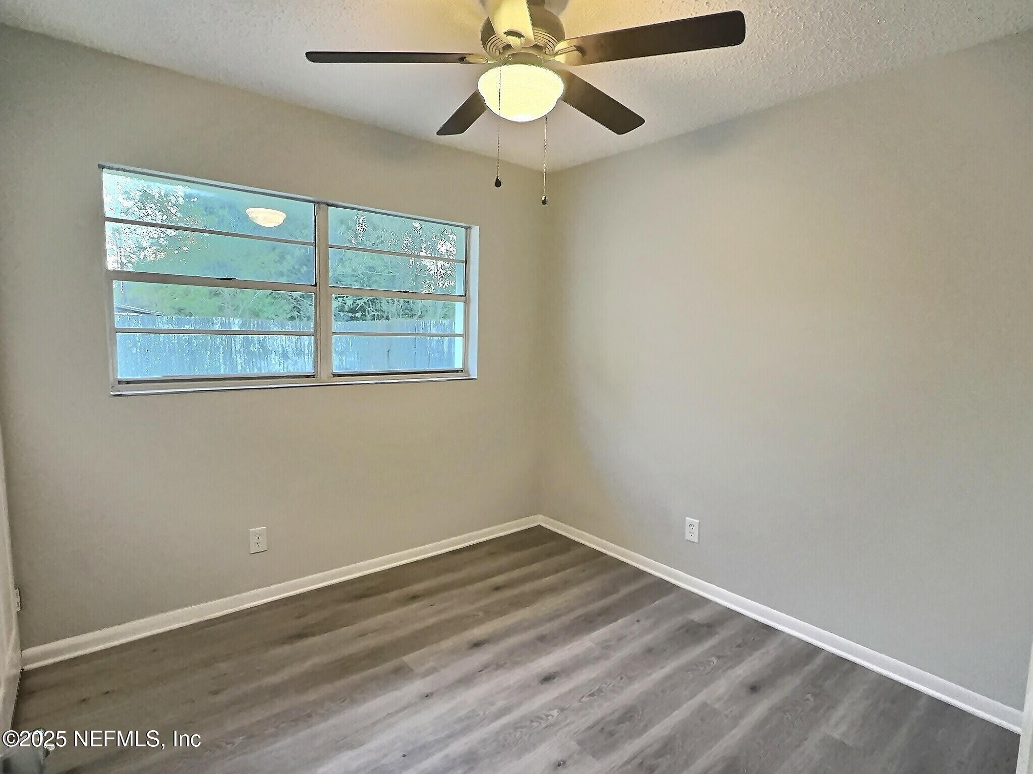 7456 Centauri Road Jacksonville, FL 32210 - Photo 15 of 26 an empty room with wooden floor fan and windows