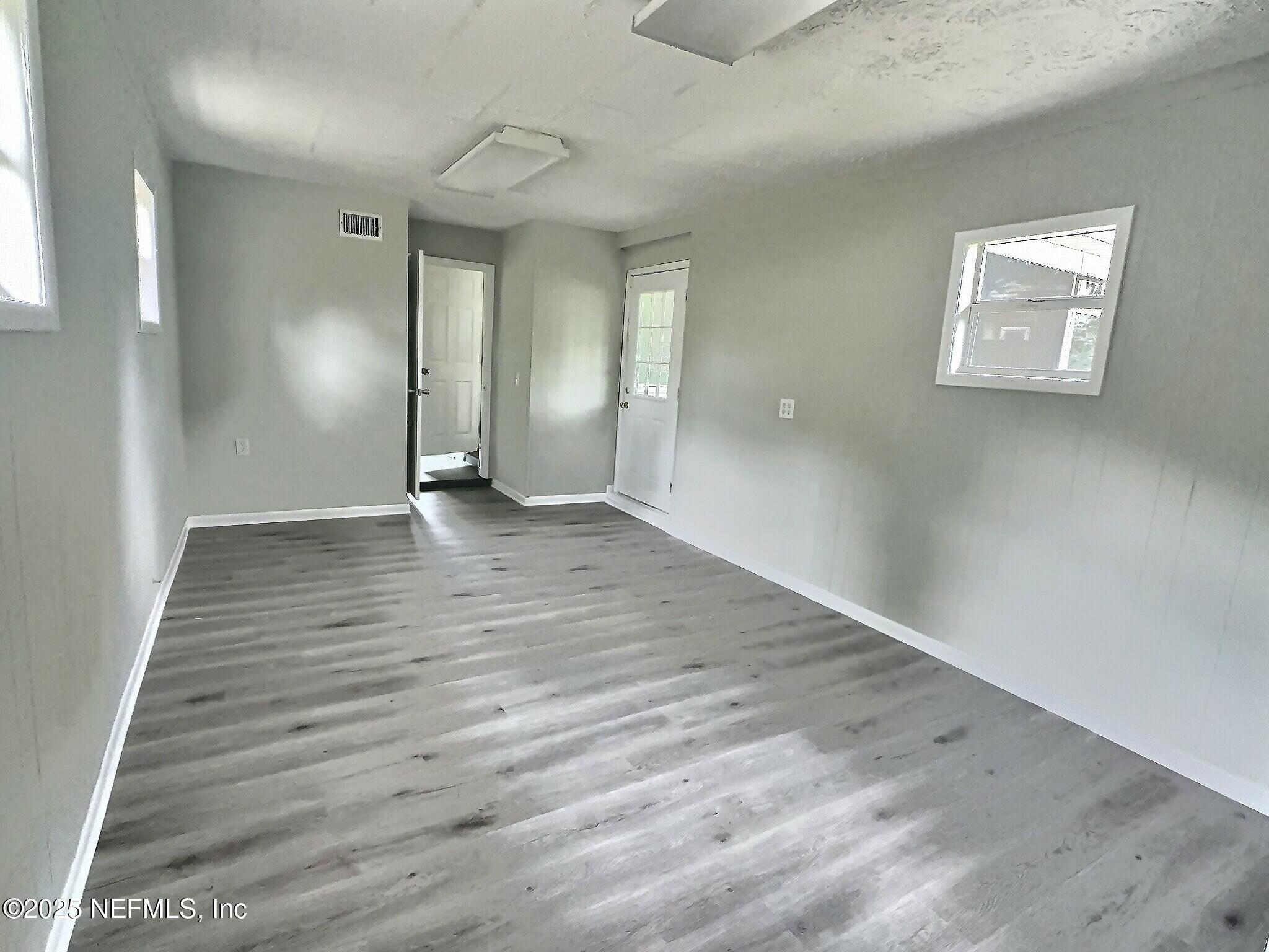 7456 Centauri Road Jacksonville, FL 32210 - Photo 21 of 26 an empty room with wooden floor and windows