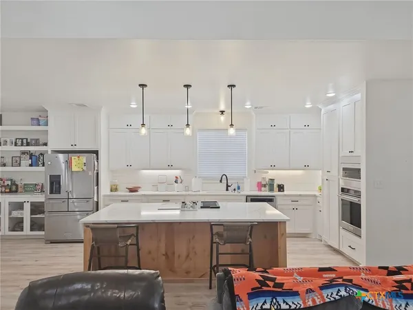 a kitchen with a white center island and chairs
