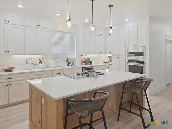 a kitchen with stainless steel appliances granite countertop a refrigerator a microwave and wooden floor