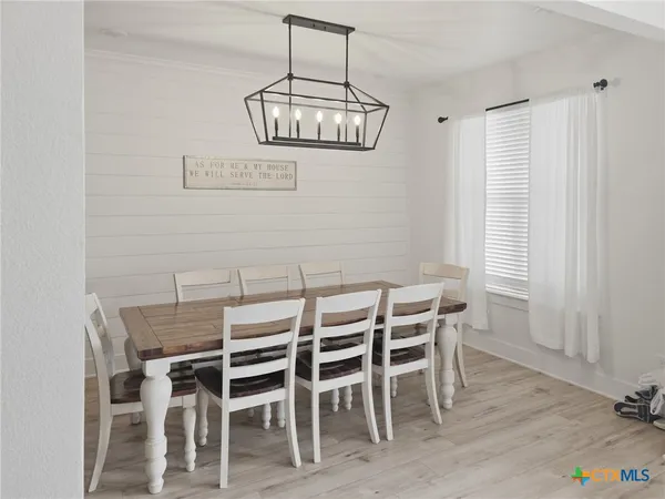 a kitchen with stainless steel appliances kitchen island a table chairs sink and cabinets