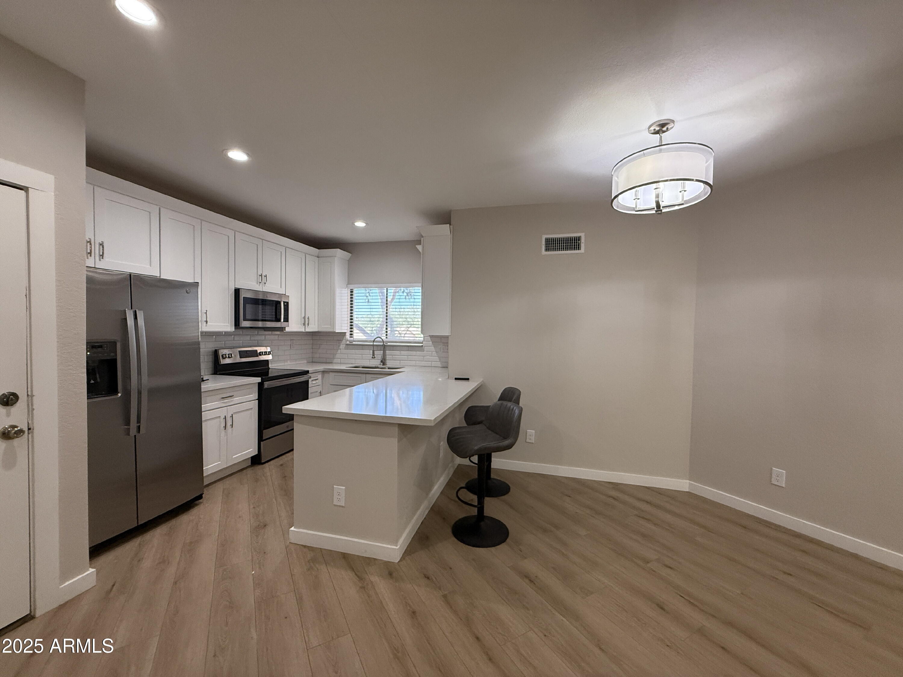 1287 North Alma School Road, Unit 207 Chandler, AZ 85224 - Photo 1 of 9 a kitchen with a refrigerator cabinets and wooden floor