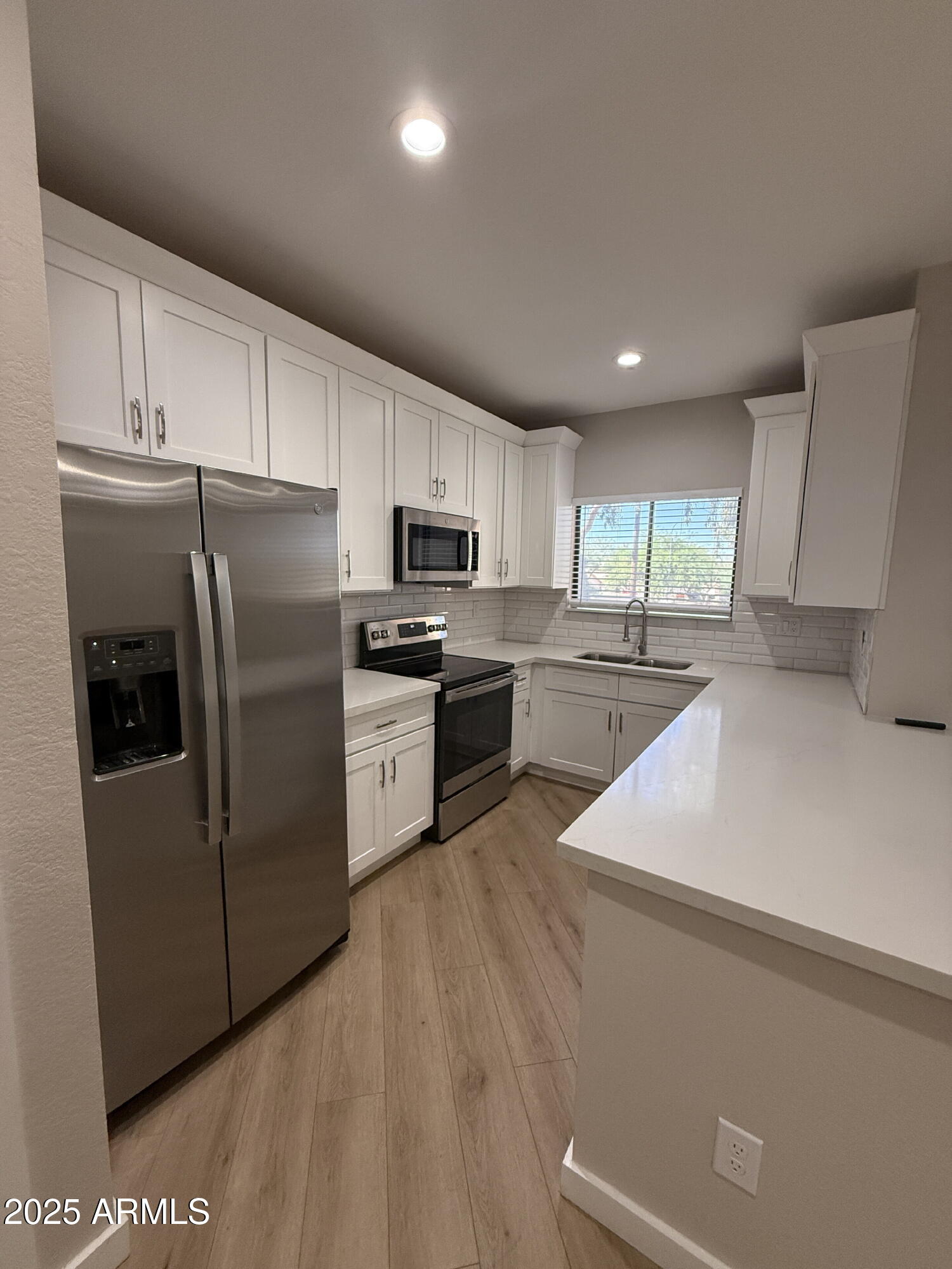 1287 North Alma School Road, Unit 207 Chandler, AZ 85224 - Photo 2 of 9 a kitchen with granite countertop a refrigerator a sink a stove top oven and white cabinets