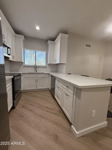 a kitchen with white cabinets appliances and a sink