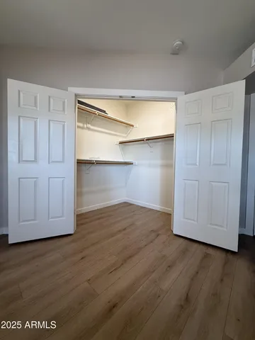 a view of an empty room with wooden floor and closet