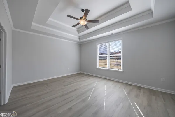an empty room with wooden floor ceiling fan and windows