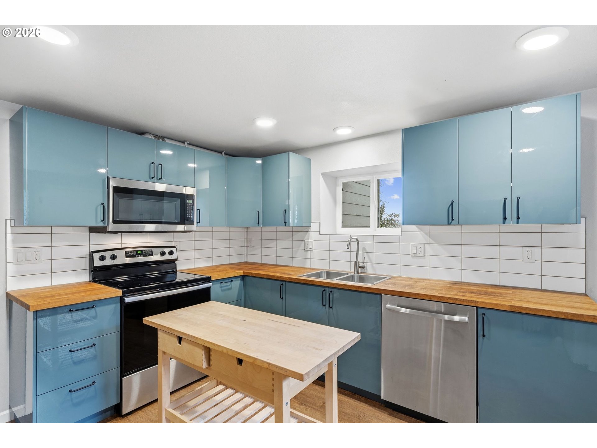 10505 Northwest 2nd Street Portland, OR 97231 - Photo 27 of 39 a kitchen with stainless steel appliances a sink dishwasher a stove a microwave oven and a dining table with wooden cabinet