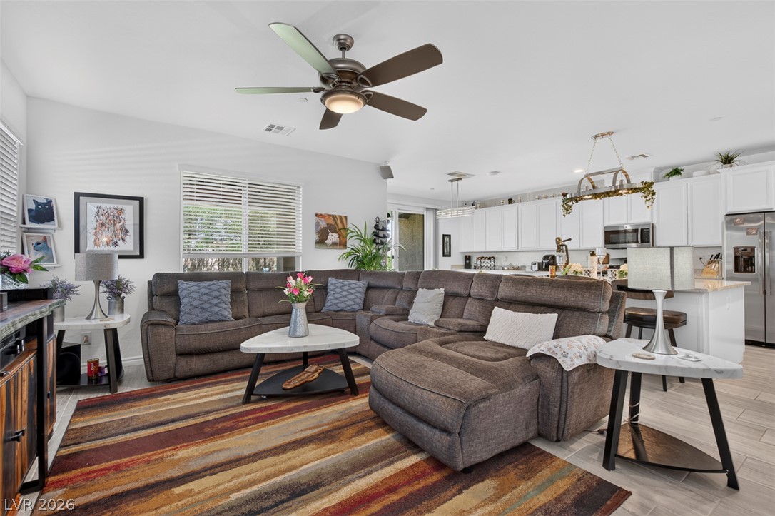 1824 Redland Ridge Street Henderson, NV 89002 - Photo 8 of 69 An inviting open-concept living area boasts a generously sized sectional and a sleek kitchen with stainless steel appliances.