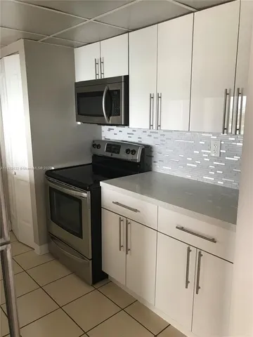 a kitchen with granite countertop white cabinets and stainless steel appliances