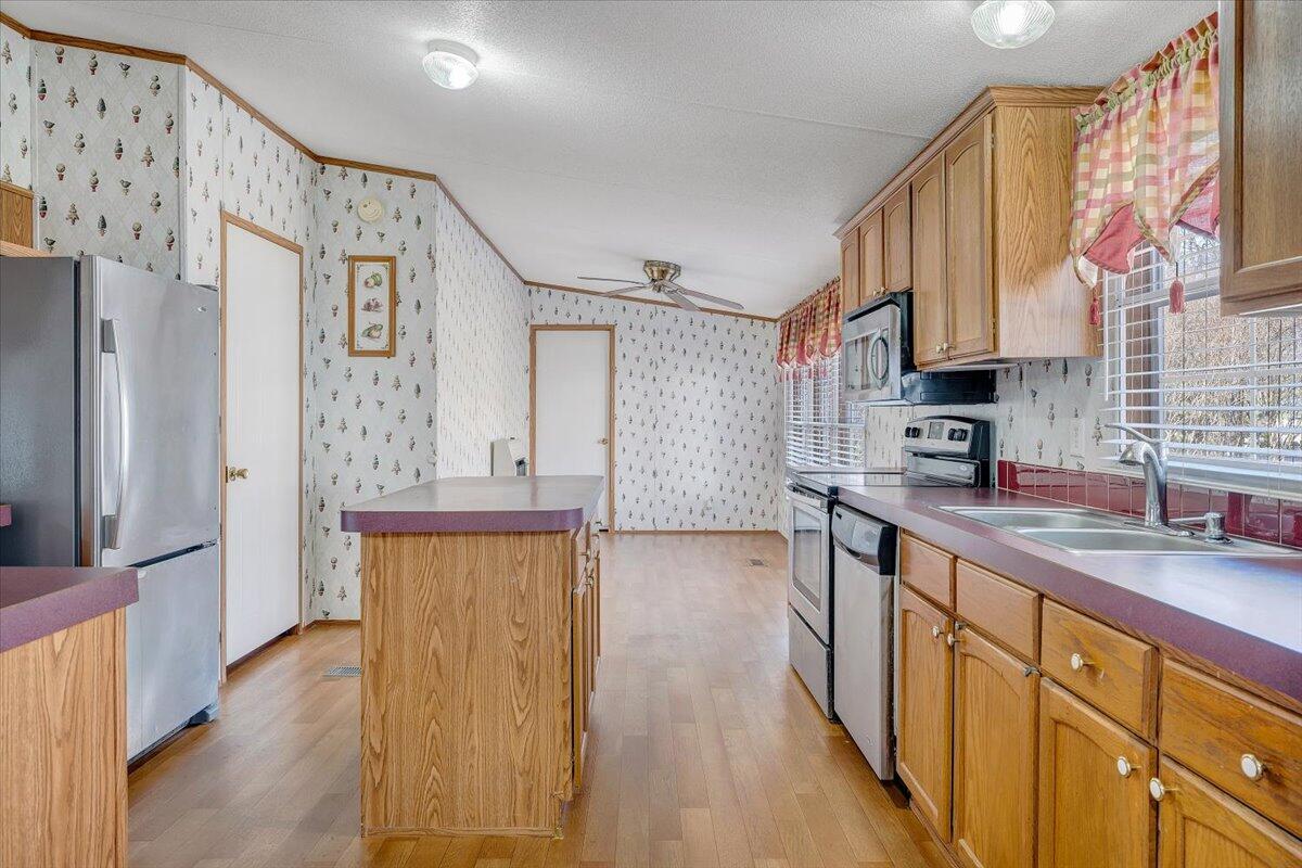 829 Moorman Mill Road Rustburg, VA 24588 - Photo 13 of 45 a kitchen with stainless steel appliances granite countertop a refrigerator a sink dishwasher and wooden cabinets with wooden floor