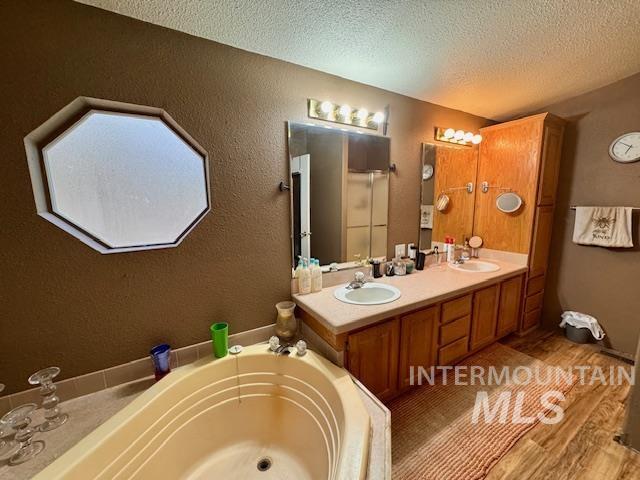 7880 Sweet Ola Highway Sweet, ID 83670 - Photo 11 of 24 Full bath with double vanity, a bath, a textured ceiling, light wood-type flooring, and a textured wall