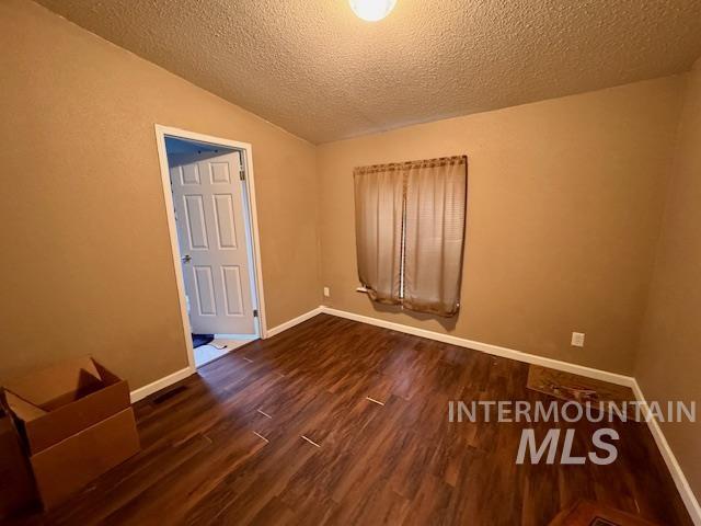 7880 Sweet Ola Highway Sweet, ID 83670 - Photo 20 of 24 Empty room featuring dark wood-style flooring, a textured ceiling, and lofted ceiling