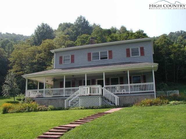 a view of house with a yard and potted plants