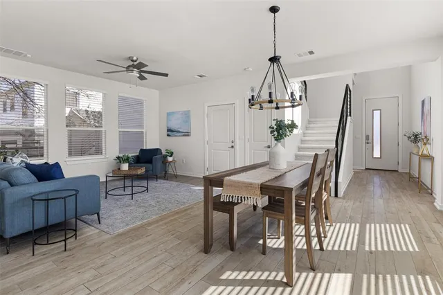 a dining room with wooden floor a chandelier a wooden table and chairs