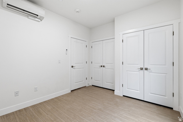 2085 North Main Street, Unit 409 Sunset, UT 84015 - Photo 7 of 17 Bedroom featuring a wall mounted mini split, light wood-style flooring, and multiple closets