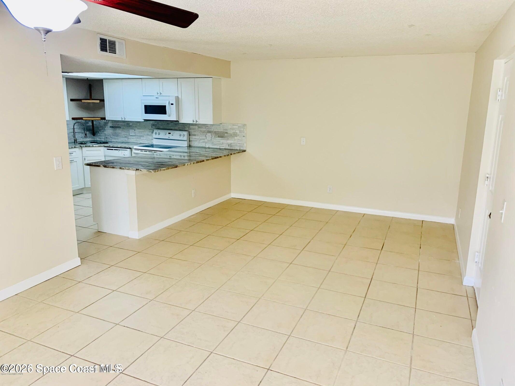 1648 Sunny Brook Lane, Unit M202 Palm Bay, FL 32905 - Photo 5 of 15 a kitchen with kitchen island a sink a counter and a stove