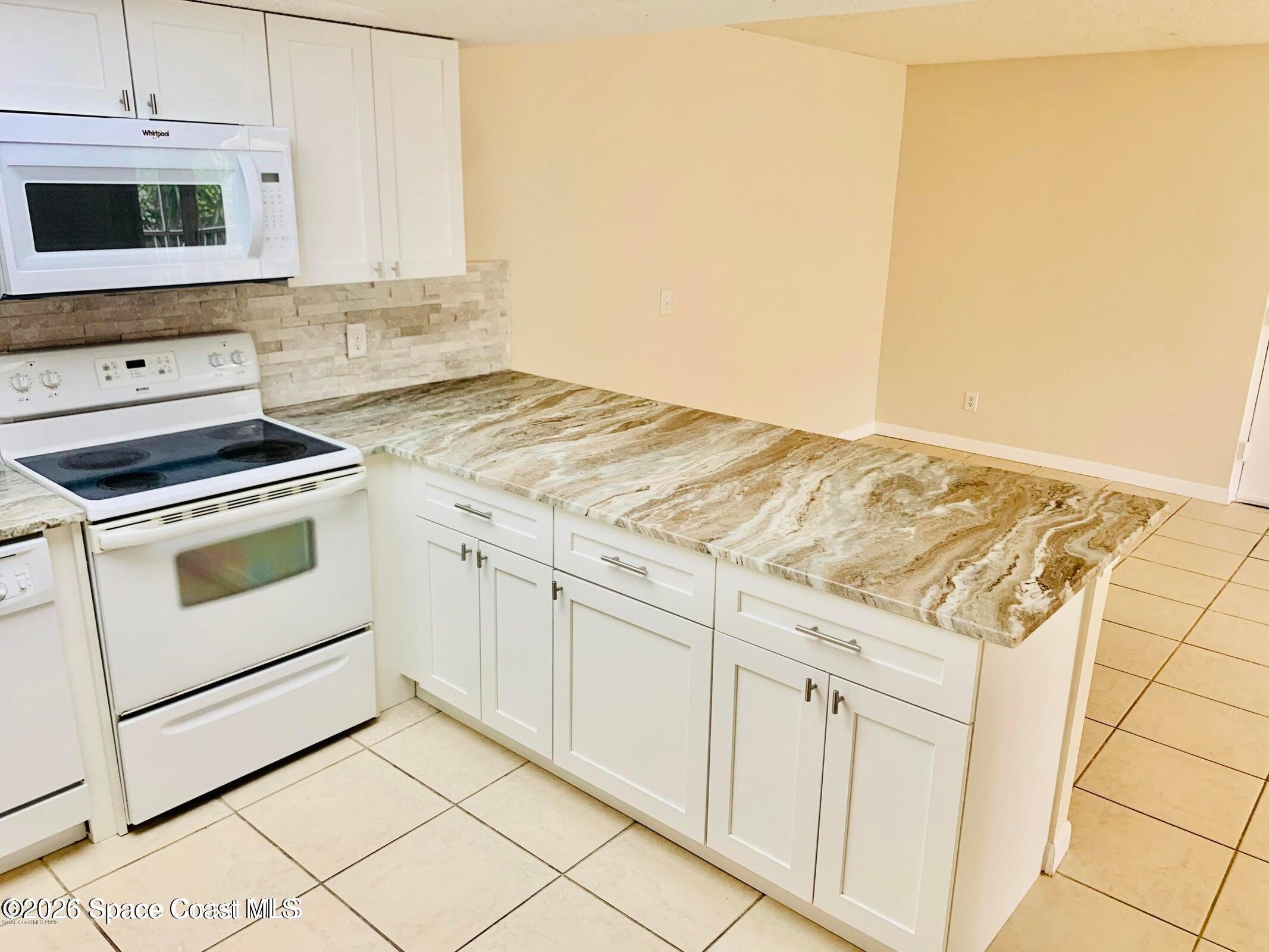 1648 Sunny Brook Lane, Unit M202 Palm Bay, FL 32905 - Photo 6 of 15 a kitchen with granite countertop white cabinets and white appliances