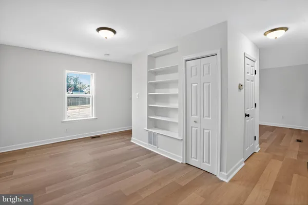 a view of an empty room with a window and wooden floor