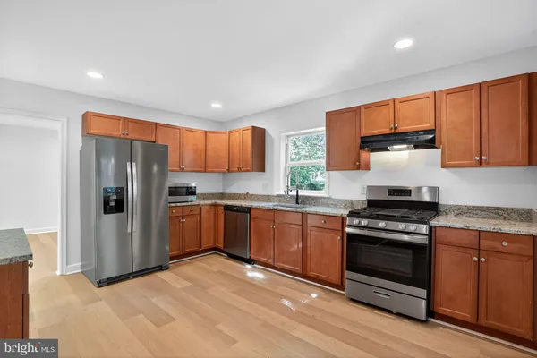 a kitchen with stainless steel appliances granite countertop a stove a refrigerator and a stove top oven