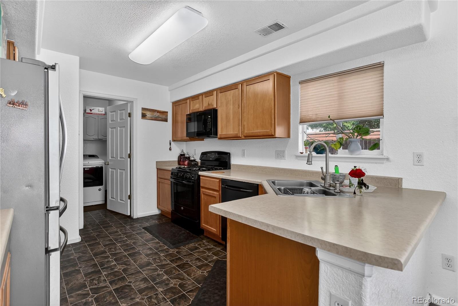20000 East Mitchell Place, Unit 71 Denver, CO 80249 - Photo 6 of 28 a kitchen with a sink a refrigerator a stove a washer and dryer