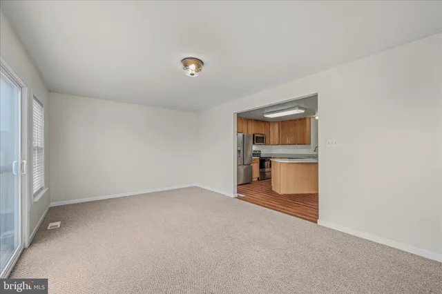 an empty room with kitchen and windows