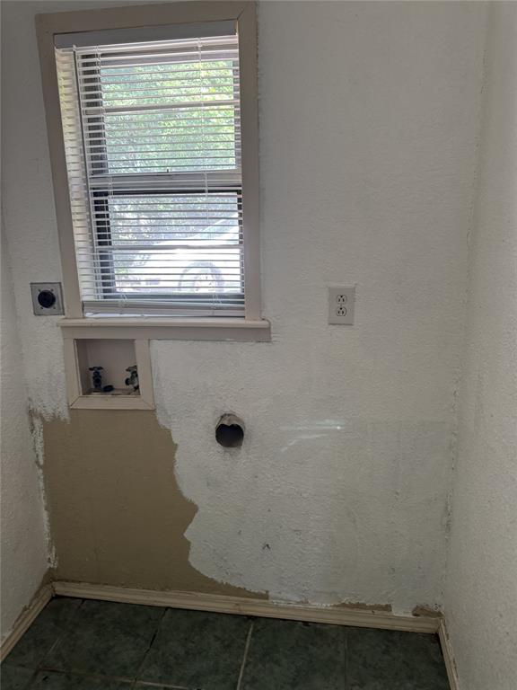 803 Ripley Avenue Ennis, TX 75119 - Photo 38 of 40 Utility space featuring a single window with horizontal blinds, textured walls, a wall-mounted electrical outlet, and dark-toned tile flooring