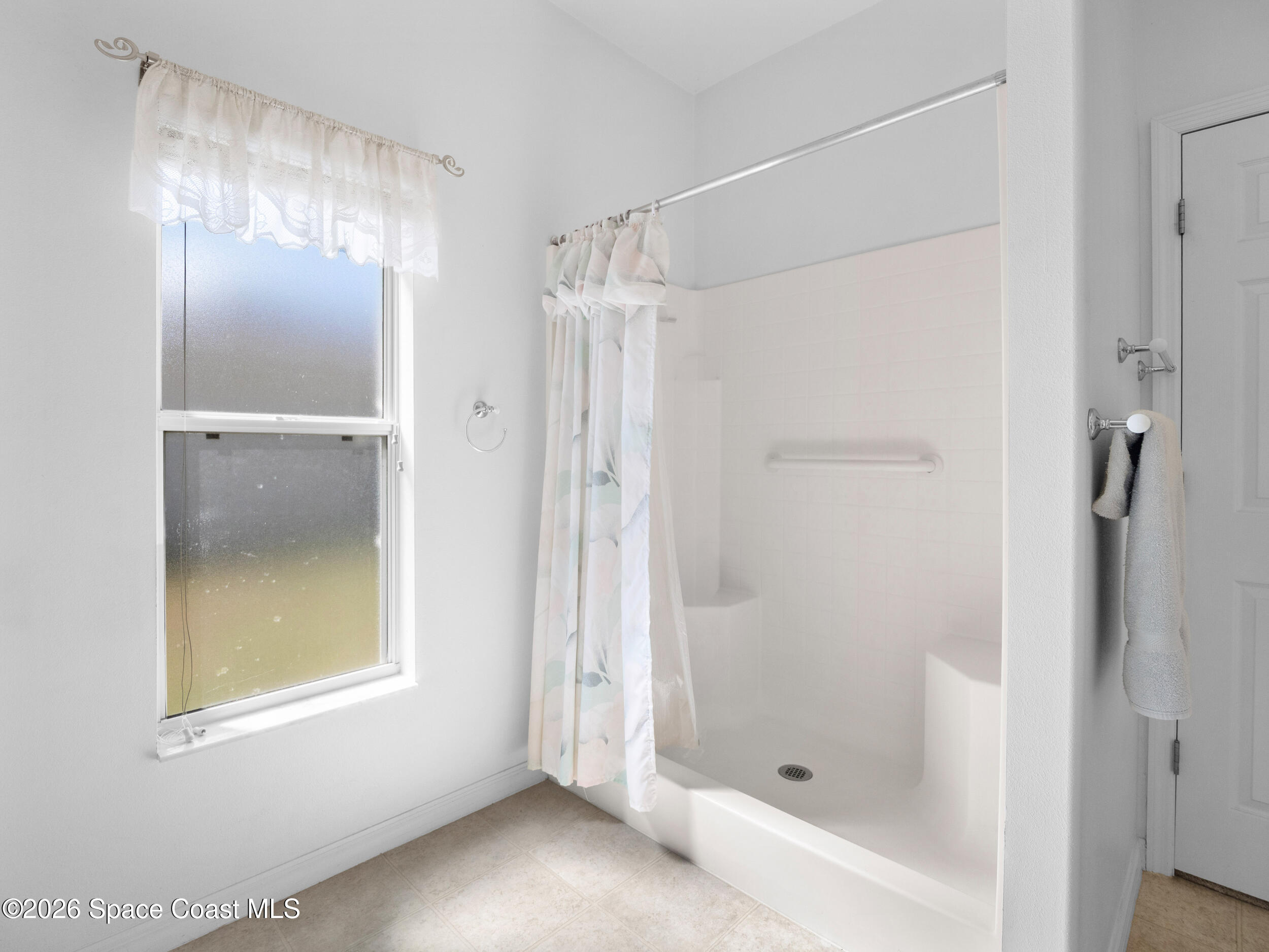 7429 Hackberry Road Cocoa, FL 32927 - Photo 27 of 51 a bathroom with a glass shower door and a window