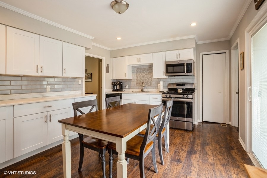 551 Ridge Circle Streamwood, IL 60107 - Photo 6 of 17 a kitchen with a table chairs refrigerator and cabinets