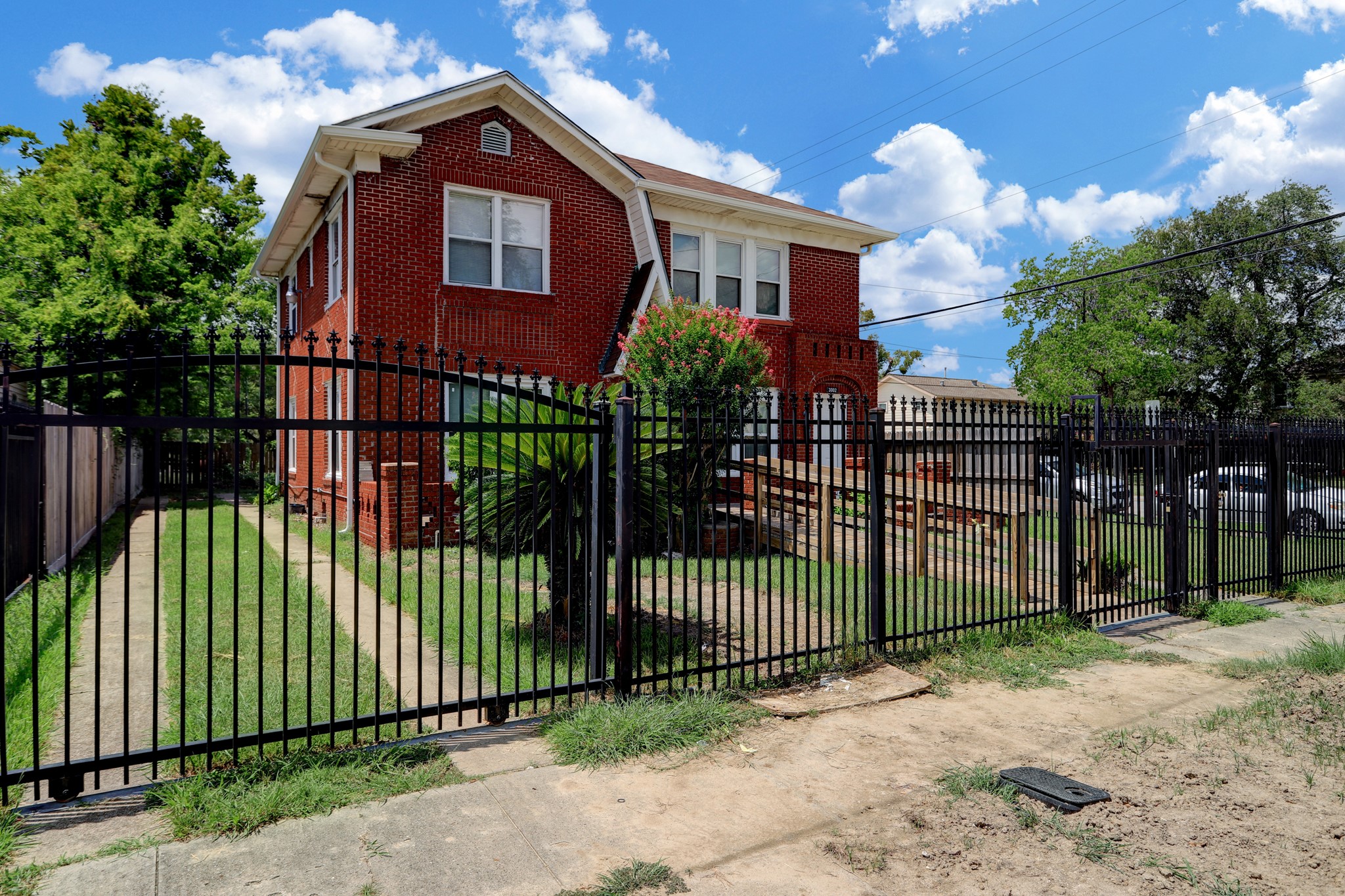 3002 Isabella Street Houston, TX 77004 - Photo 2 of 18 a view of a brick house with large trees and plants next to a yard