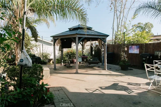 a view of patio with table and chairs under an umbrella with potted plants