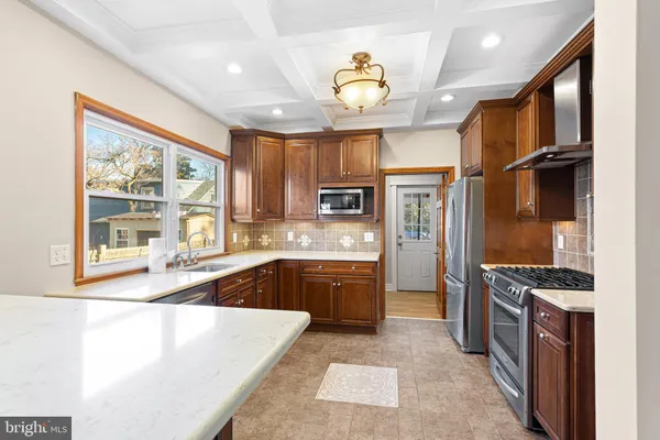 a large kitchen with stainless steel appliances granite countertop a stove refrigerator and a sink with large windows