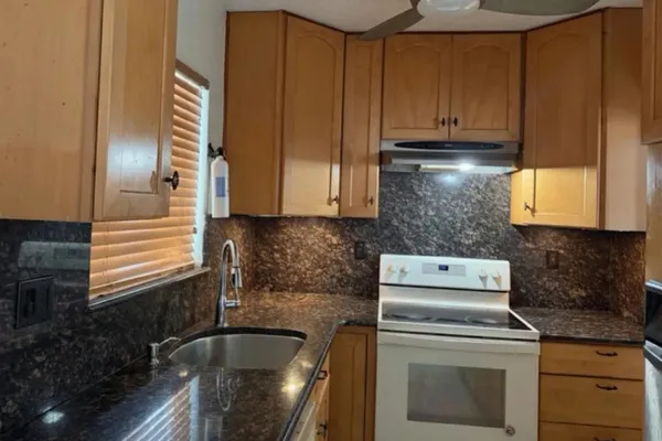 a kitchen with granite countertop wood cabinets and stainless steel appliances