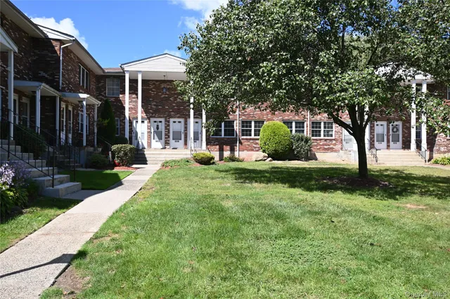 a front view of a house with garden and trees